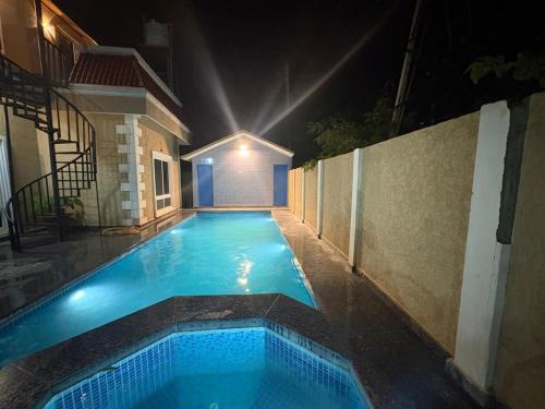 an empty swimming pool at night with a building at Golden Nest Farms 3BHK Private Pool by Homeyhuts in Venkatāpur