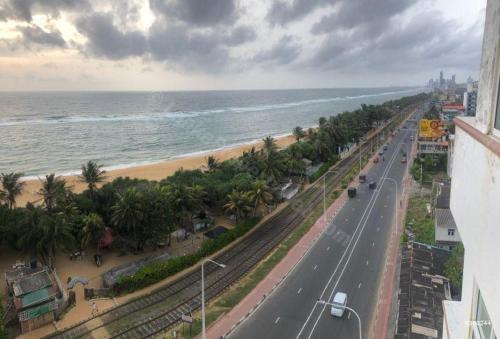 a road next to a beach with the ocean at Windsor apartments Dehiwala in Dehiwala