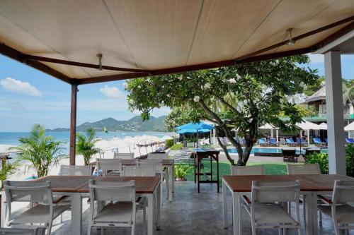 a restaurant with tables and chairs and the beach at KC Beach Club & Pool Villas in Chaweng