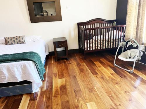 a bedroom with a crib and a wooden floor at A Gorgeous Mansion for Jasper Vacation in Hinton