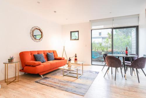 an orange couch in a living room with a table at Insurgentes Area APT Balcony, Outdoor Lounge in Mexico City