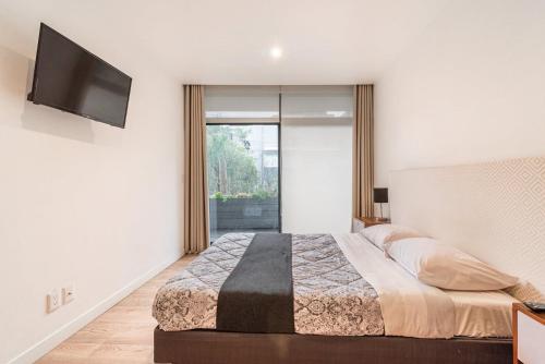 a bedroom with a bed and a flat screen tv at Insurgentes Area APT Balcony, Outdoor Lounge in Mexico City