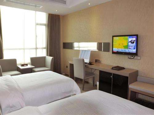 a hotel room with a bed and a desk with a computer at GreenTree Alliance Shenzhen Shekou Sea World Hotel in Shenzhen