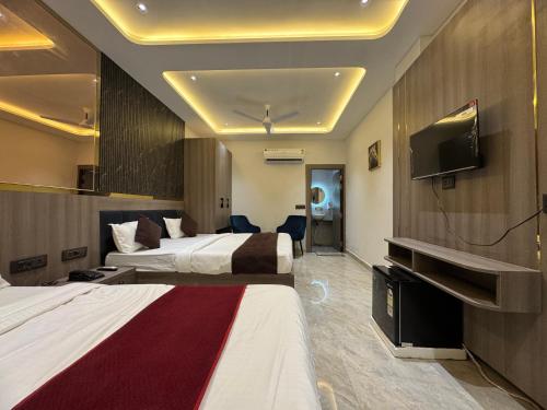 a hotel room with two beds and a flat screen tv at C2 Hotel in Mathura