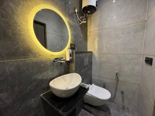 a bathroom with a sink and a mirror and a toilet at C2 Hotel in Mathura