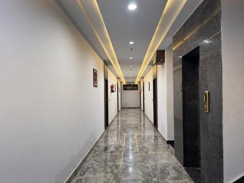 a hallway with white walls and a long hallway with black doors at C2 Hotel in Mathura