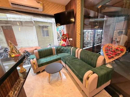 a living room with a green couch and chairs at Hotel Apsara in Ujjain