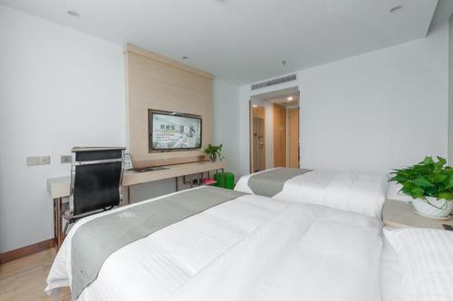 a bedroom with two beds and a desk and a television at GreenTree Inn Wuhu Eshan Road University City in Wuhu