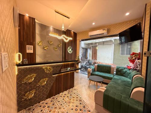 a living room with a green couch and a tv at Hotel Apsara in Ujjain