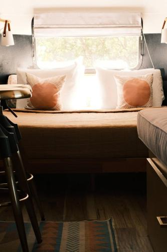 a bed with two pillows and a window in a room at Silver Bullet Airstream, El Mistico Glamping Ranch in Nogal
