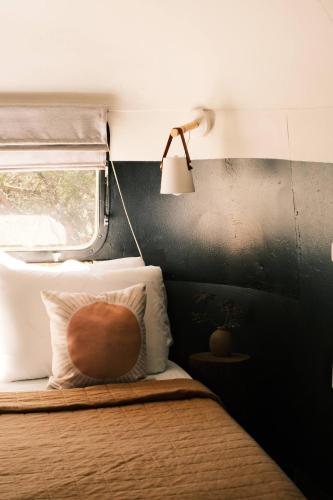 a bedroom with a bed with a lamp and a window at Silver Bullet Airstream, El Mistico Glamping Ranch in Nogal