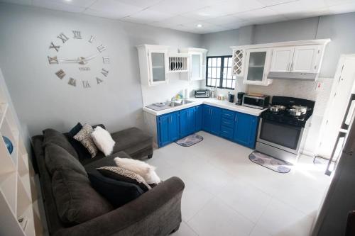 a kitchen with a couch and a clock on the wall at Stacys Place #3 Studio Apartment in Port-of-Spain