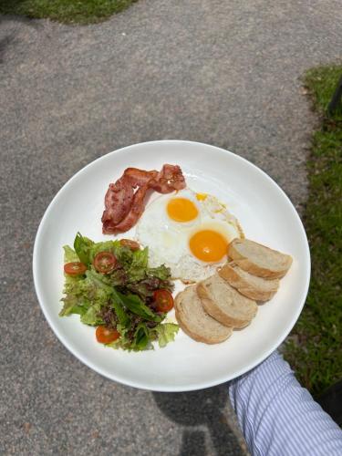 a plate of breakfast food with eggs bacon and greens at Little Bird in Prachuap Khiri Khan