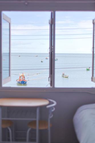 a window view of the ocean with boats in the water at Hostel 126 Cafe' & Bar in Prachuap Khiri Khan