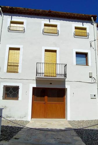 a white house with a brown door and a balcony at Cal Serraller in Miravet