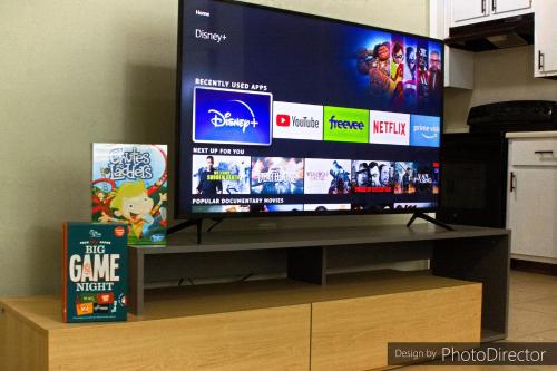 a flat screen tv sitting on top of a entertainment center at No Checkout Work! NEW Family Friendly Stay! in College Station
