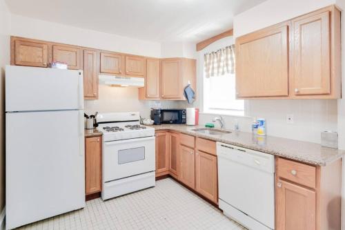 a kitchen with wooden cabinets and a white refrigerator at Colleges Bistros History Come See The Main Line in Bryn Mawr