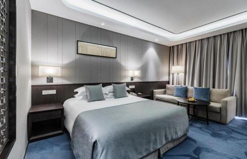 a hotel room with a large bed and a chair at International Conference Hotel Nanjing in Nanjing