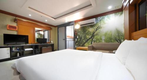 a bedroom with a white bed and a large window at Hotel Head-One in Uijeongbu