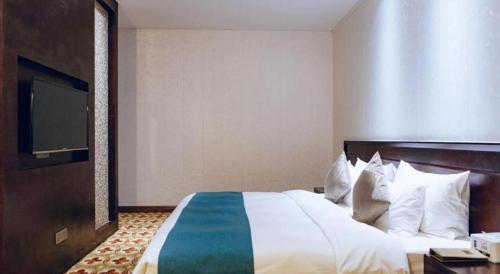 a hotel room with a large bed with a flat screen tv at Manhatton Hotel Beihai in Beihai