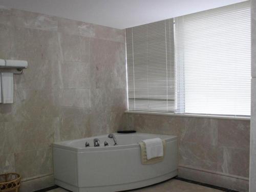 a white bath tub in a bathroom with a window at Manhatton Hotel Beihai in Beihai