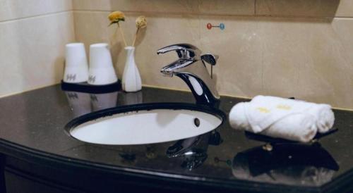 a bathroom sink with a faucet and towels on a counter at Manhatton Hotel Beihai in Beihai