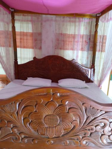 a wooden bed with a wooden head board with curtains at Old Town Hotel in Kandy