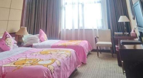 a hotel room with two beds with pink sheets at Huangshan International Hotel in Huangshan
