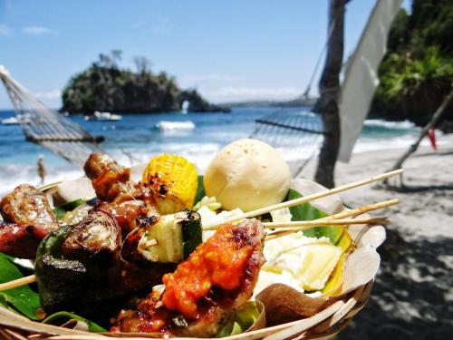 a bowl of food on a beach with a basket of food at Sandy Beach Bungalows By EHM in Koh Rong Sanloem