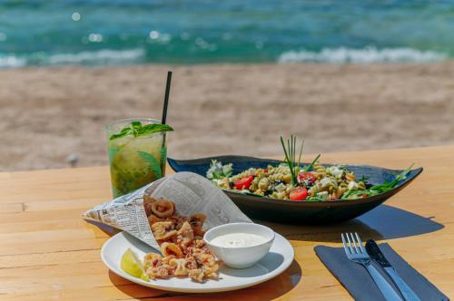 a table with a plate of food and a salad and a drink at Sandy Beach Bungalows By EHM in Koh Rong Sanloem