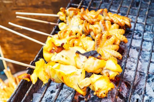 a bunch of food on a grill with chop sticks at Sandy Beach Bungalows By EHM in Koh Rong Sanloem