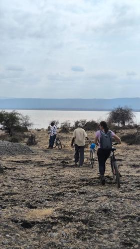 three people walking on a beach with their bikes at Jangwani River View Suits in Mto wa Mbu