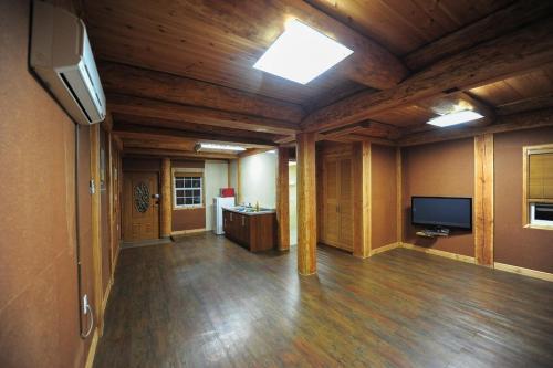an empty living room with a television and wooden ceilings at Boryeong Rich Valley Log Village Pension in Boryeong