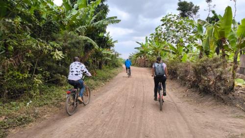 three people riding bikes down a dirt road at Jangwani River View Suits in Mto wa Mbu