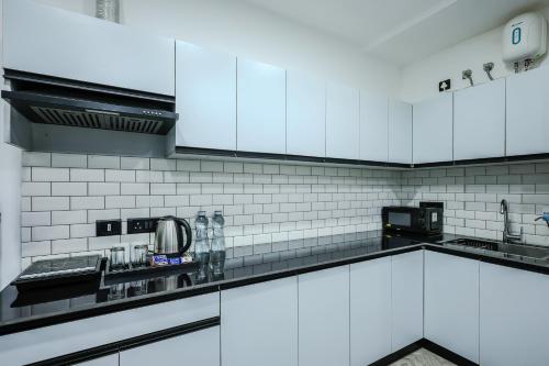 a kitchen with white cabinets and black appliances at BedChambers Luxury Apartment Near Golf course Road in Gurgaon