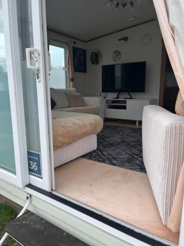 a living room with a couch and a tv at 2 Bedroom Mini Lodge near the beach in Walton-on-the-Naze