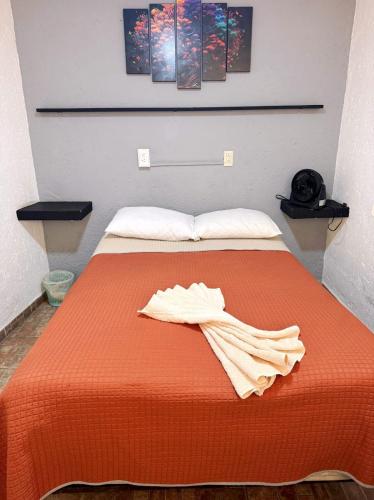 a bed with an orange bedspread with a towel on it at Casita del Árbol in Mexico City