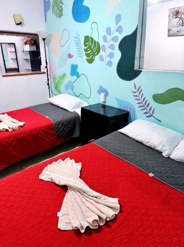 a bedroom with two beds and a red blanket at Casita del Árbol in Mexico City