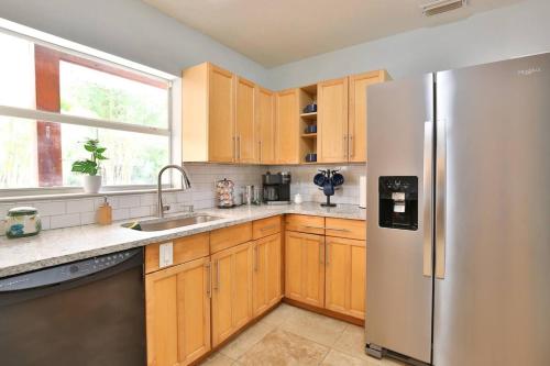 a kitchen with wooden cabinets and a stainless steel refrigerator at Coastal Villa W Amazing Courtyard - Splash Pad! in Sarasota