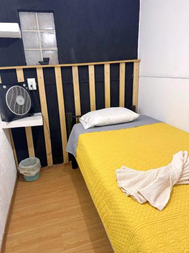 a bedroom with two beds with a yellow bedspread and a fan at Casita del Árbol in Mexico City