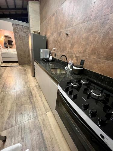a kitchen with a stove and a sink at Casa, 01 Suíte, Ar-Cond, Área Gourmet e Garagem Ampla in Montes Claros