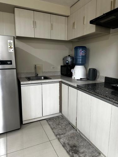 a kitchen with white cabinets and a sink and a refrigerator at Jojies Crib Horizons101 2bedrooms in Cebu City