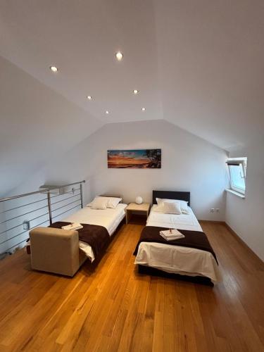 two beds in a large room with wooden floors at Oasis Blue in Korčula