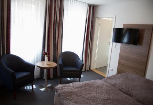 a hotel room with a bed and two chairs and a television at La Flamme Wertheim garni in Wertheim