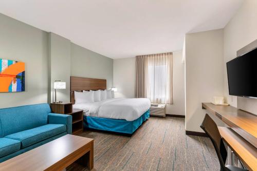 a hotel room with a bed and a blue couch at MainStay Suites Lancaster Dallas South in Lancaster