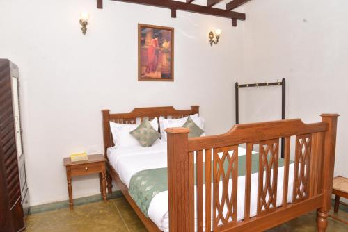 a bedroom with a wooden bed and a mirror at Esparan Heritage in Puducherry