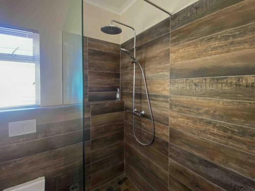 a bathroom with a shower with a glass door at Green Parrot Holiday Apartment in Fish hoek