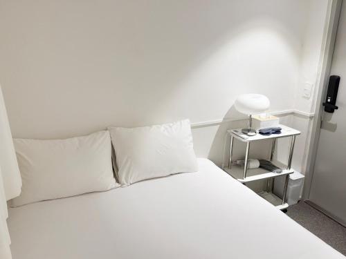 a white bed with white pillows and a side table at nook Inn in Seoul
