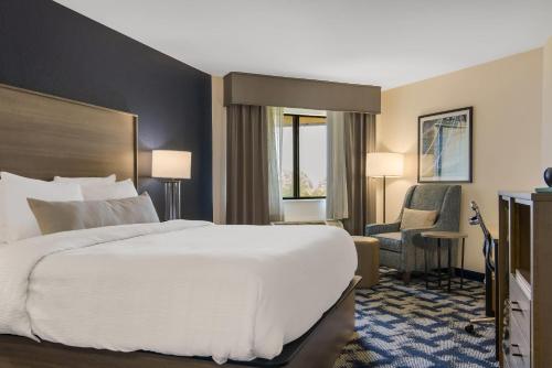 a hotel room with a large bed and a chair at The Inn on Maritime Bay, an Ascend Collection Hotel in Manitowoc