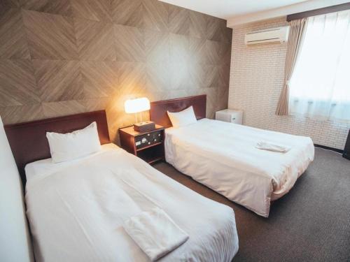 a hotel room with two beds and a window at Hotel Areaone Miyazaki in Miyazaki